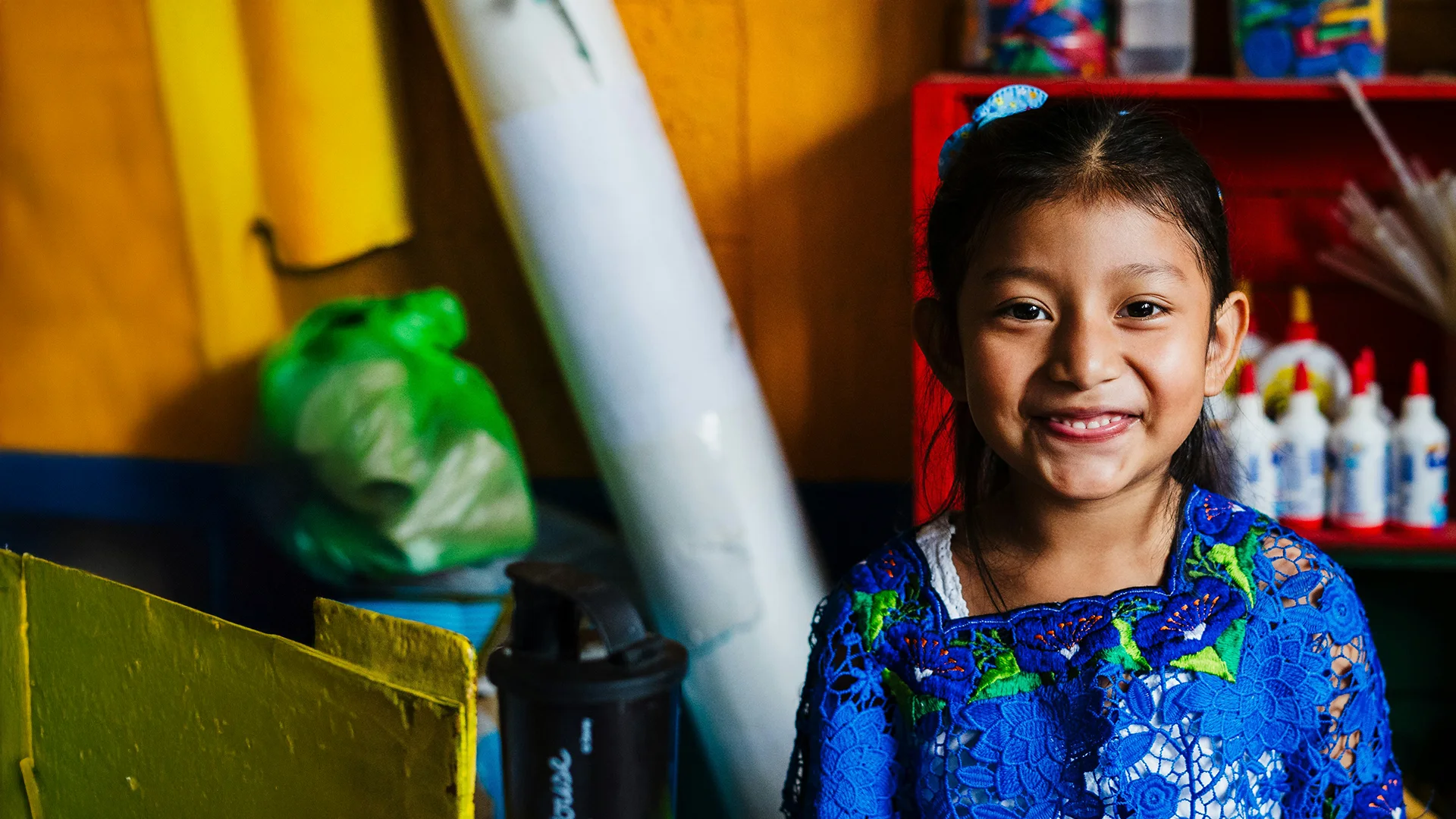 A smiling girl in an embroidered blouse in a classroom